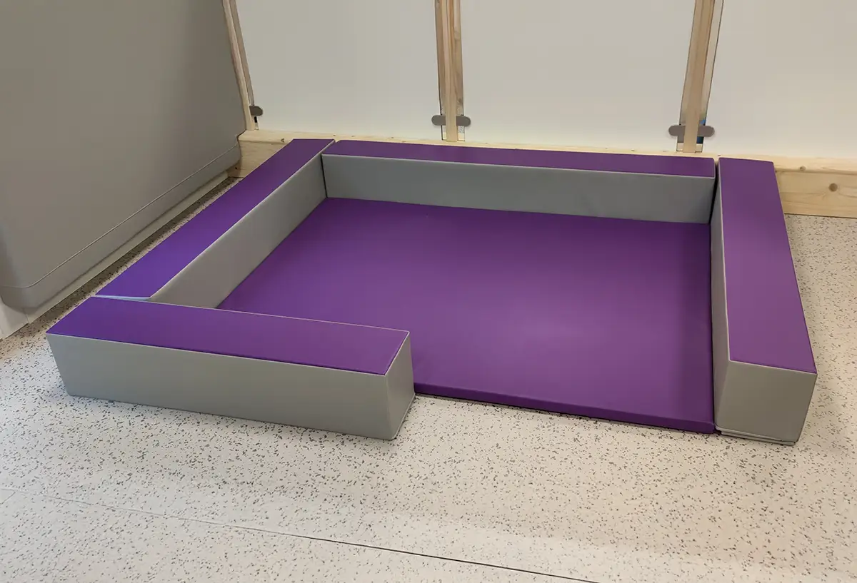 espace de regroupement avec tapis et poutres pour crèche